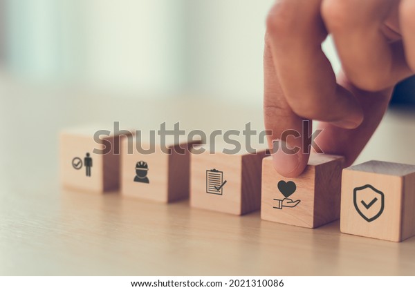 Safety at work concept. Hand holds cubes wooden\
block with safety icons; safety first, protections, health,\
regulations and insurance.  Used for banner, beautiful bright\
background and copy\
space.