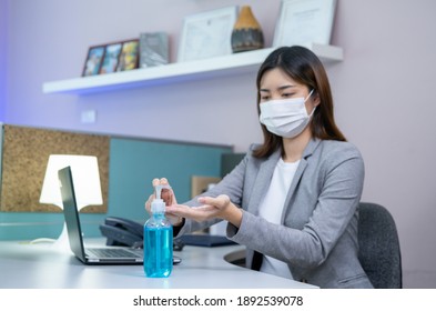 Safety Work Place Concept, Young Businesswoman Wearing Face Mask And Using Sanitizer Hand Gel While Working On A Computer In The Office.