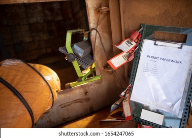 Safety Workplace Permit To Work Paper Clipping On Isolation Control Permit Board Together With Red Personal Danger Locks And Tags At Confined Space Entry Exit Door Ventilation Fan                  