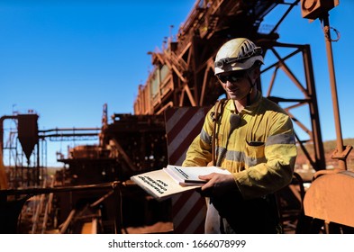 Safety workplace site planner supervisor wearing fall protection white hard hat work uniform radio holding planner inspection checklist and working at heights permit book prior start high risk work  