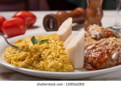 Saffron Risotto With Parmigiana Steak Beef. Risoto And Beef In A White Plate On Wooden White Background. Soft Light, Angle View. Italian Food. Risotto With Curcuma