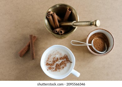 Sahlep, milk and orchid roots hot drink in a white cup with cinnamon. Local name is "salep". Wooden background. Drink concept and idea. Selective focus on sahlep and sticks.