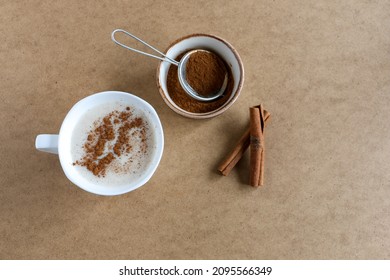 Sahlep, milk and orchid roots hot drink in a white cup with cinnamon. Local name is "salep". Wooden background. Drink concept and idea. Selective focus on sahlep and sticks.