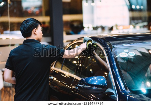 SAIGON EXHIBITION AND CONVENTION CENTER (SECC),\
HO CHI MINH CITY, VIETNAM - OCTOBER 2018: Unidentified man car\
cleaner. A man cleaning car with microfiber cloth, car detailing\
(or valeting) concept