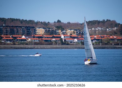 Sail Boat And Speed Boat With Small Coastal City (Stavanger Norway) In The Background