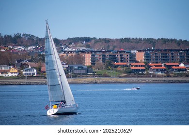 Sail Boat And Speed Boat With Small Coastal City (Stavanger Norway) In The Background