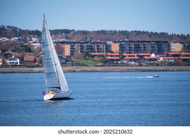 Sail Boat And Speed Boat With Small Coastal City (Stavanger Norway) In The Background