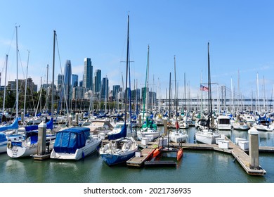 Sail boats and yachts docked at South Beach Harbor Marina. Background skyscrapers of downtown and of San Francisco - Oakland Bay Bridge - San Francisco, California, USA - 2021