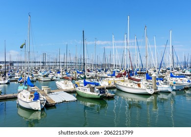 Sail boats and yachts docked at South Beach Harbor Marina. Background San Francisco - Oakland Bay Bridge - San Francisco, California, USA - 2021