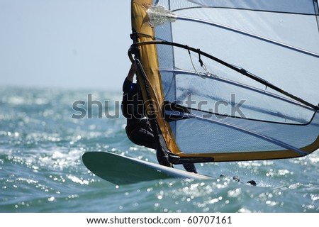 A sailboarder glides across the ocean water.