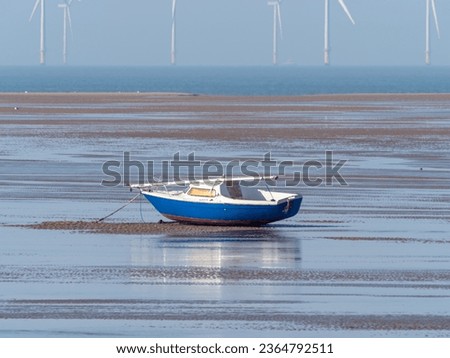 sailboat aground at low tide with wind turbines in the distance