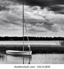 Sailboat anchored on lake during stormy day in monochrome image