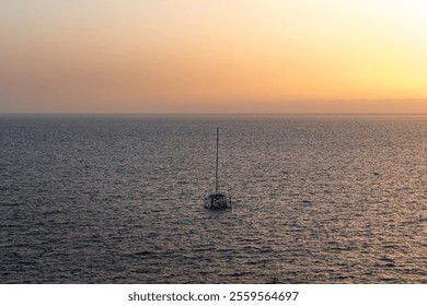 Sailboat anchored peacefully at sunset on calm ocean waters - Powered by Shutterstock