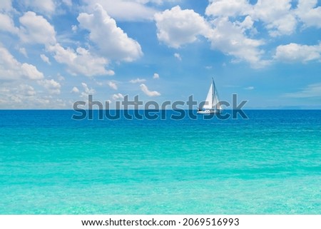 A sailboat in blue turquoise seawater near Phuket island in summer season during travel holidays vacation trip. Andaman ocean, Thailand. Tourist attraction with blue cloud sky.