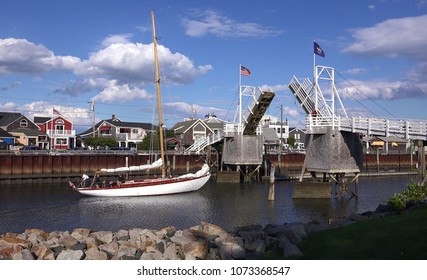  Sailboat heads out to sea under cross over walking draw bridge, scenic blue sky clouds, Perkins Cove Ogunquit, Maine USA - September 18, 2014