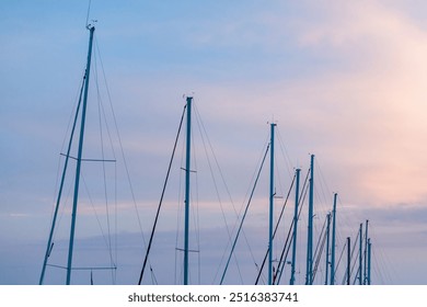 Sailboat masts against a pastel sky at sunset - Powered by Shutterstock