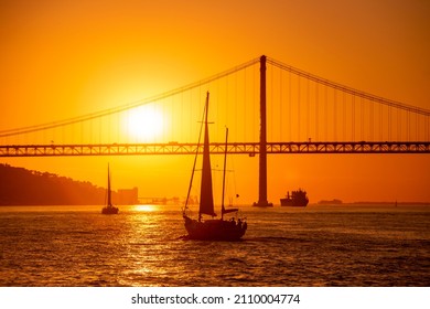 Segelboot mit Ponte 25 de Abril oder 25 April Bridge im Rio Tejo nahe der Stadt Lissabon in Portugal.  Portugal, Lissabon, Oktober 2021