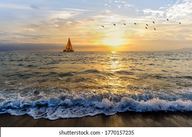 A Sailboat is Sailing Along the Ocean as a Vivid Colorful Sunset is in the Background and Birds Flying - Powered by Shutterstock