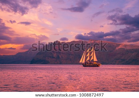 Sailboat in Santorini, Greece. Sailing ship navigate near an island in Cyclades. The photo is taken at sunset.