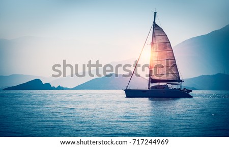 Sailboat in the sea in the evening sunlight over beautiful big mountains background, luxury summer adventure, active vacation in Mediterranean sea, Turkey