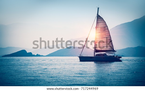 Sailboat in the sea in the\
evening sunlight over beautiful big mountains background, luxury\
summer adventure, active vacation in Mediterranean sea,\
Turkey