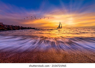 A Sailboat Silhouette Sailing Against A Colorful Sunset Sky And A Flock Of Birds Flying Overhead