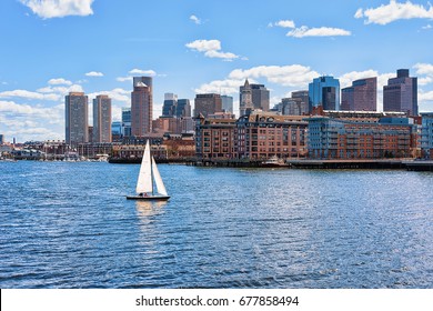 Sailboat traveling across Charles river with the skyline of the city in the background in Boston, America