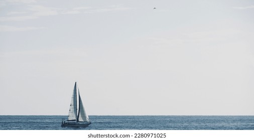 Sailboat in the water with space for text. White sailing boat. Boat sailing on summer vacation in the Mediterranean Sea. Sailing boat racing with white sails in open sea.
 - Powered by Shutterstock