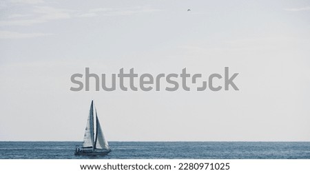 Sailboat in the water with space for text. White sailing boat. Boat sailing on summer vacation in the Mediterranean Sea. Sailing boat racing with white sails in open sea.
