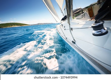 Sailboat at windy day floats in clear water / sea