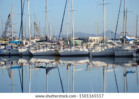 sailboats anchored in the port of Alghero and their reflections on the water