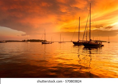 Sailboats and a beautiful red and orange sunset in Penobscot Bay in Maine