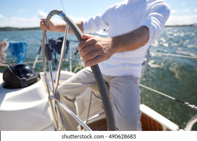 Sailing, Age, Tourism, Travel And People Concept - Close Up Of Senior Man Steering Wheel And Navigating Sail Boat Or Yacht Floating In Sea