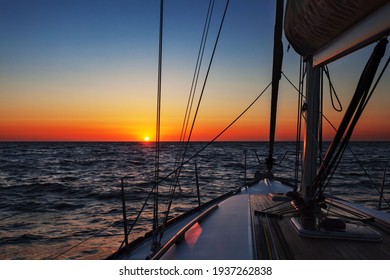 Sailing boat at calm open sea at colorful sunset