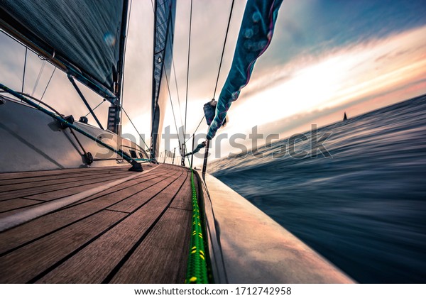 Sailing boat deck in motion on sunset, brown shiny\
wooden deck on foreground, skyline on sunset on background, long\
exposure photo