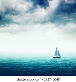 Sailing Boat On Blue Sea With Heavy Storm Clouds, Conceptual Image Of Uncertain Future