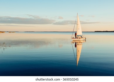 Sailing boat on a calm lake with reflection in the water. Serene scene landscape. Horizontal photograph. - Powered by Shutterstock