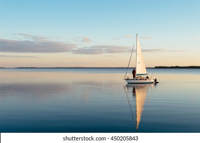 Sailing boat on a calm lake with reflection in the water. Serene scene landscape. Horizontal photograph. - Powered by Shutterstock