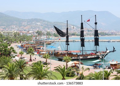 Sailing boat with a pirate flag stands in the bay and waiting for tourists