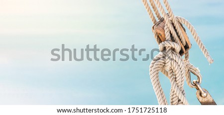 Sailing boat pulley, block and tackle with moored nautical rope. Panoramic water nautic background with copy space.

