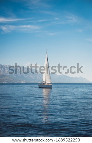 Sailing boat in the sea against the backdrop of mountains	