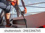 Sailing boat, securing the sail on the boat. Crew member tightens the sail on the sailing boat. 
