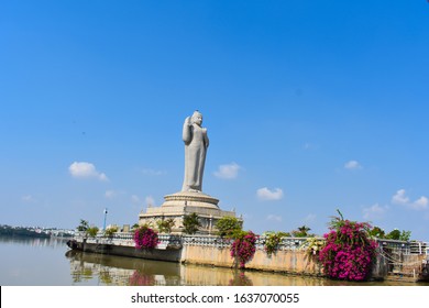 sailing by the buddha statue with pink bougainvillea plants in the middle of hussain sagar lake in Hyderabad, Telengana, India.