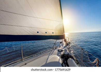 Sailing at calm weather with sun. A view from the yacht's deck to the bow and sails. Sail boat with set up sails gliding in open sea. Greece, Europe