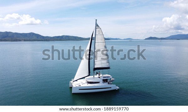 Sailing catamaran with open sails.\
Sailing\
catamaran in the middle of the sea in a tropical landscape. Sailing\
boat with open sails