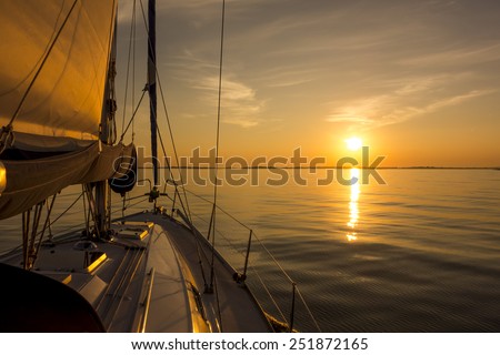 Sailing into the sunset. Yacht with sails and sunset