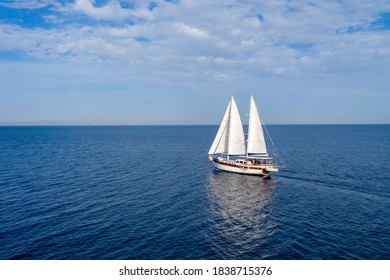 Sailing. Luxury yacht ship boat with white sails in the open sea. Wooden vintage sailboat, cloudy blue sky background. Aegean sea Greece
