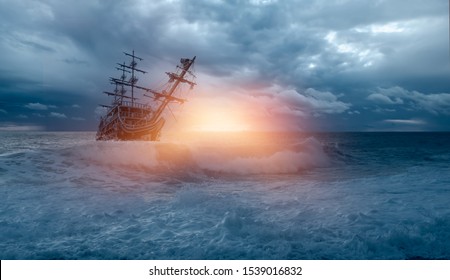 Sailing Old Ship In Storm Sea Against Heavy Sunset Clouds