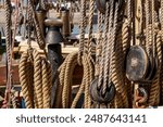 Sailing ship lines, pulleys and securing equipment tied down for the day. Deck and ropes, rigging on a wooden tall ship sail yacht. Close up view