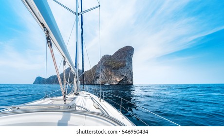 Sailing vessel moves in a sea under power towards the island